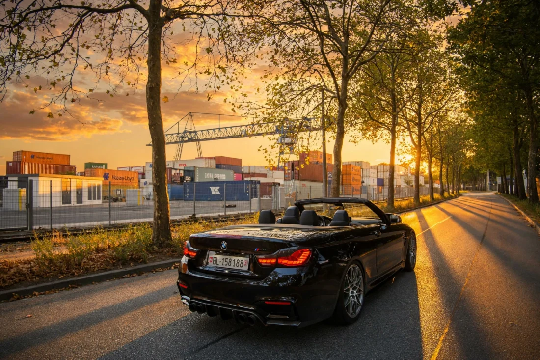 BMW M4 convertible on a tree-lined avenue at sundown