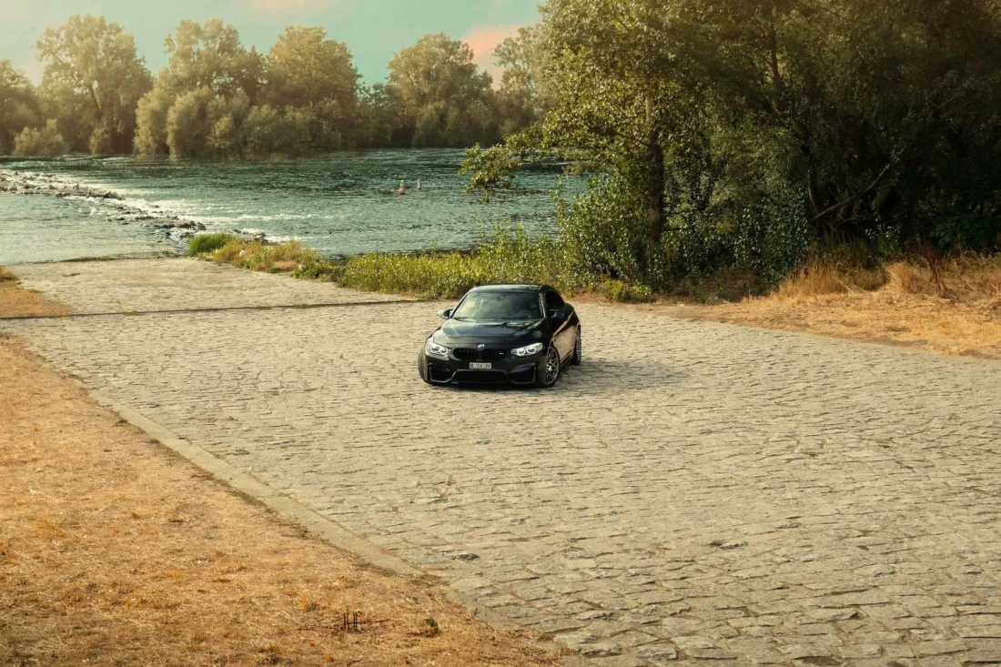 Black BMW M4 on riverside cobblestones